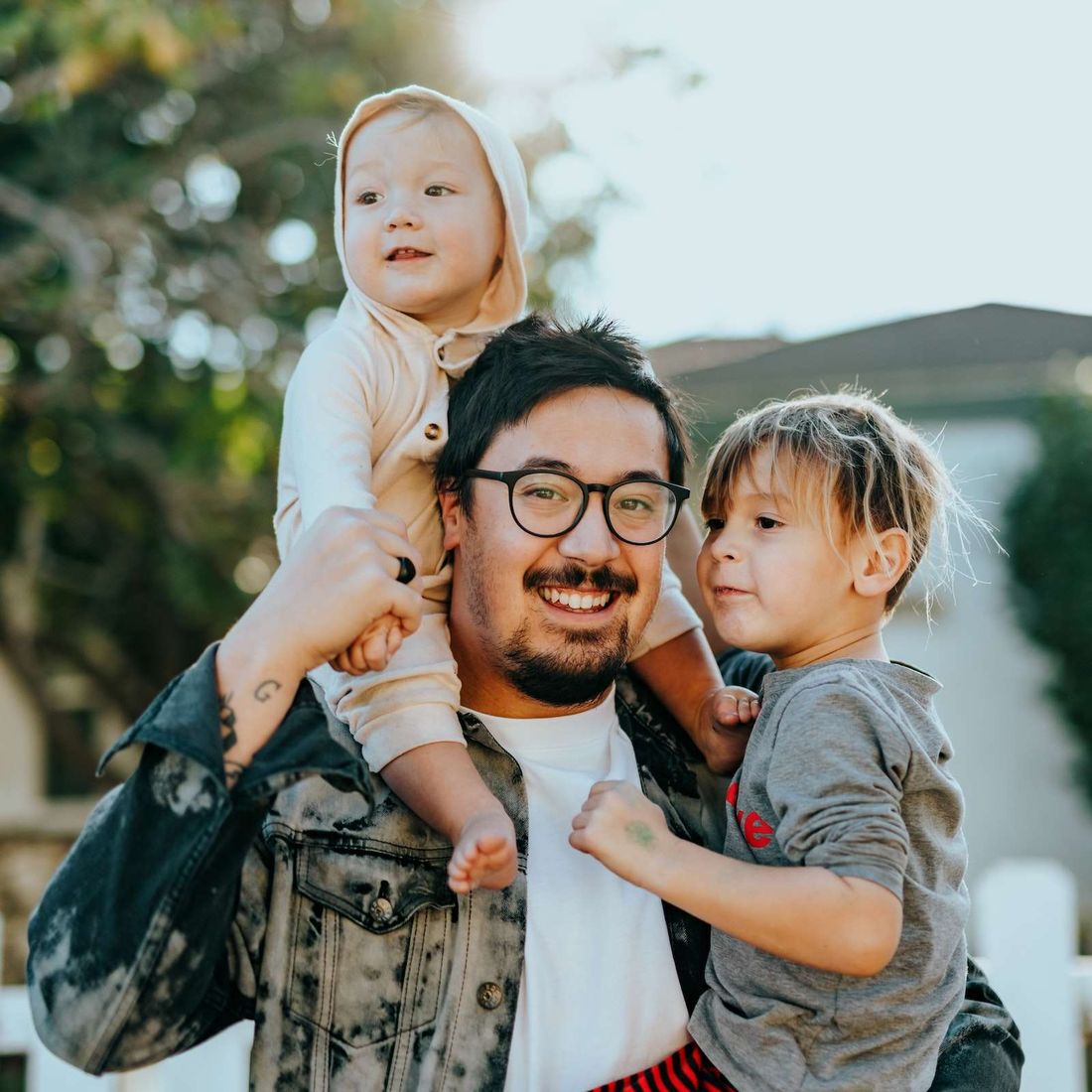 A dad smiling with his two young children